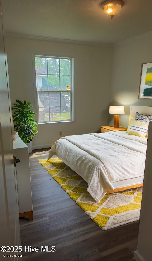 bedroom featuring baseboards, wood finished floors, and crown molding
