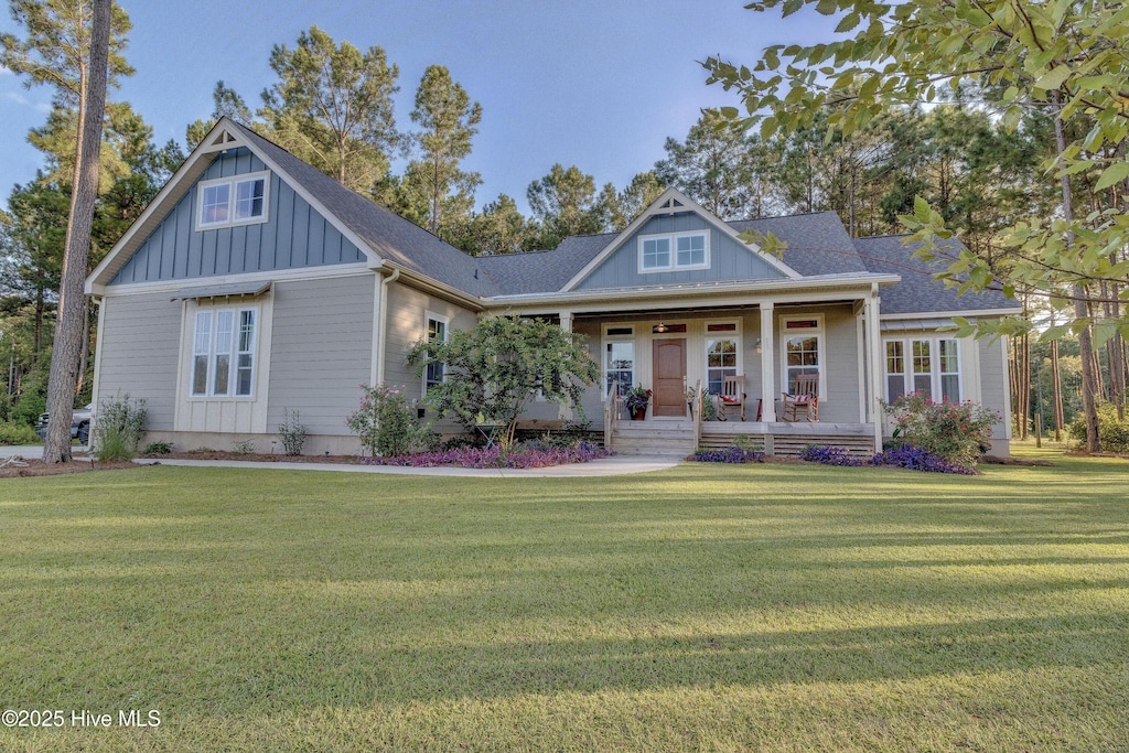 craftsman inspired home featuring covered porch, board and batten siding, and a front yard