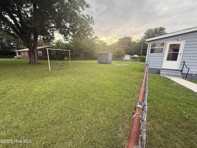 16980 Barnes Dr, Laurinburg, NC 28352 - yard at dusk with entry steps, a shed, a lawn, and an outdoor structure