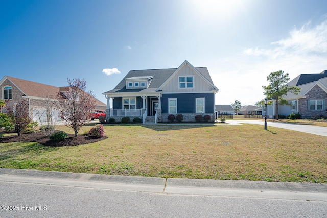 8945 Chesterfield Dr NW, Calabash, NC 28467 - craftsman house featuring board and batten siding, covered porch, a front yard, driveway, and stone siding