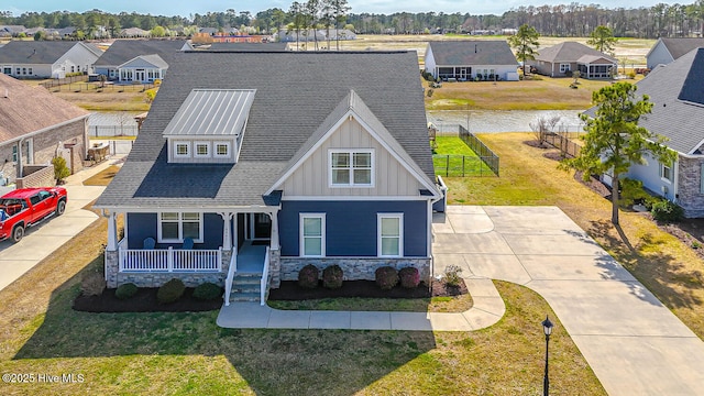 8945 Chesterfield Dr NW, Calabash, NC 28467 - view of front of house with board and batten siding, a residential view, covered porch, stone siding, and roof with shingles