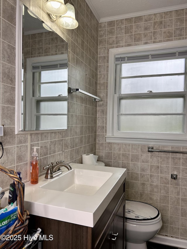 bathroom featuring toilet, vanity, ornamental molding, and tile walls