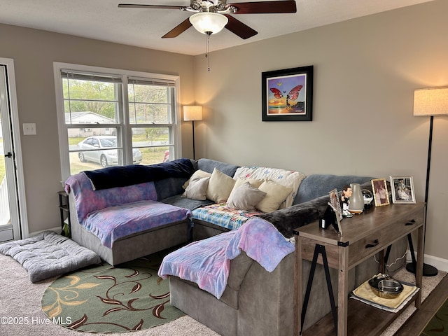 living area with baseboards and ceiling fan
