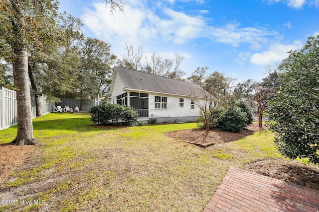 back of property with a sunroom, fence, and a lawn