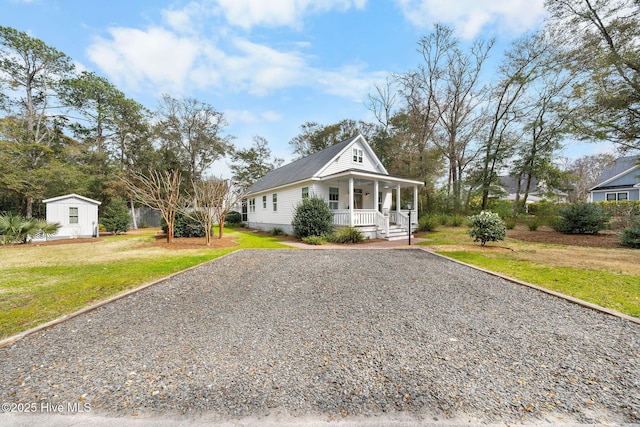 view of front of home featuring gravel driveway, covered porch, and a front yard