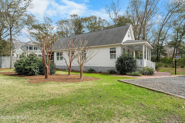 exterior space with ceiling fan, a shingled roof, covered porch, and a yard