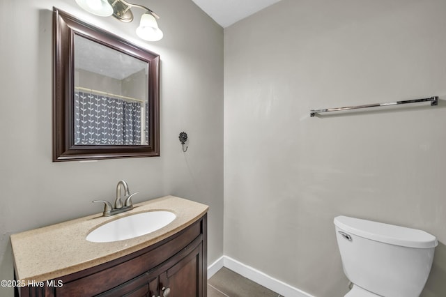 bathroom featuring toilet, vanity, and baseboards