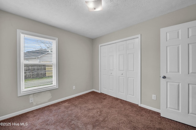 unfurnished bedroom with a closet, a textured ceiling, baseboards, and carpet