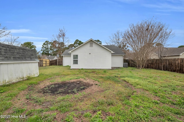 back of property with a lawn, an outdoor structure, and a fenced backyard