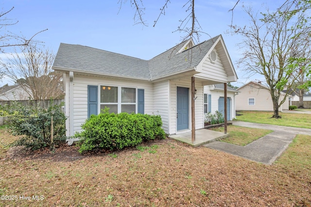 bungalow with fence, a front lawn, and a shingled roof