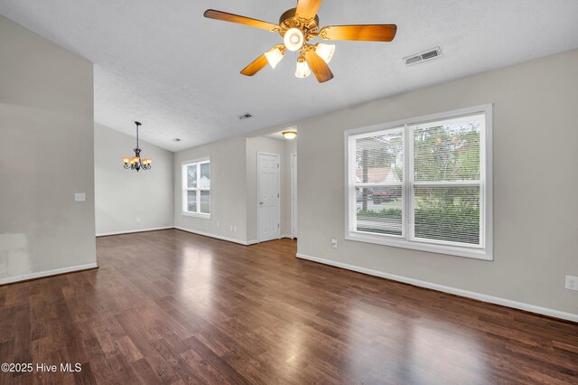 unfurnished living room featuring visible vents, baseboards, lofted ceiling, ceiling fan with notable chandelier, and dark wood-style floors