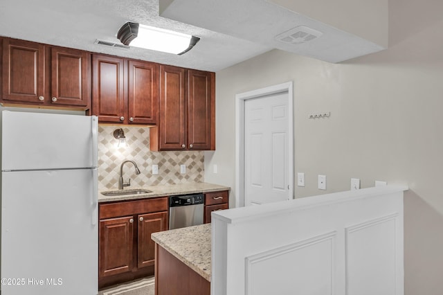 kitchen featuring dishwasher, visible vents, freestanding refrigerator, and a sink
