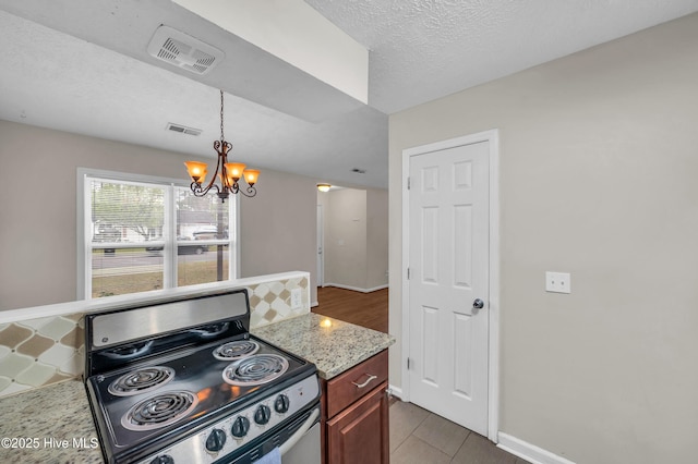 kitchen featuring light stone countertops, visible vents, hanging light fixtures, stainless steel range with electric stovetop, and a notable chandelier