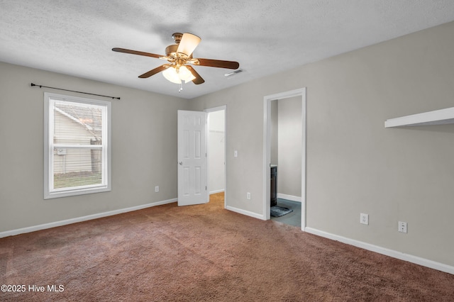 unfurnished bedroom featuring visible vents, a textured ceiling, carpet floors, baseboards, and ceiling fan