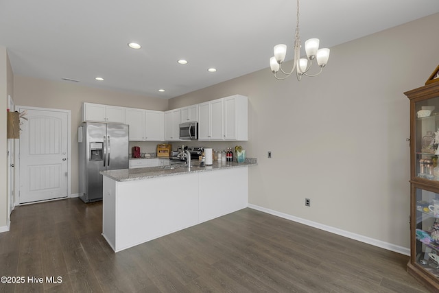 kitchen featuring stainless steel appliances, a peninsula, baseboards, a sink, and recessed lighting