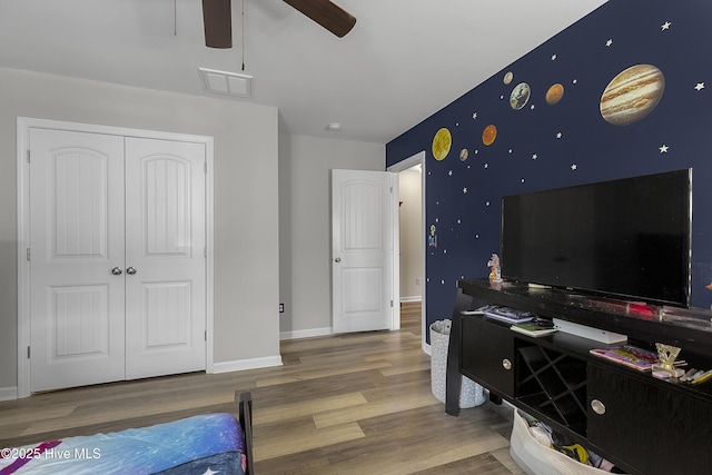 bedroom with wood finished floors, a closet, baseboards, and ceiling fan