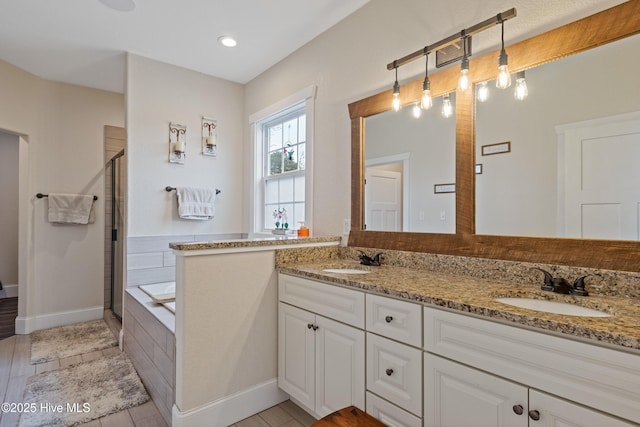 bathroom featuring a bath, double vanity, a stall shower, and a sink