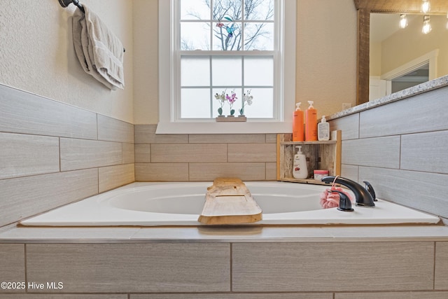 bathroom featuring a bath and a textured wall