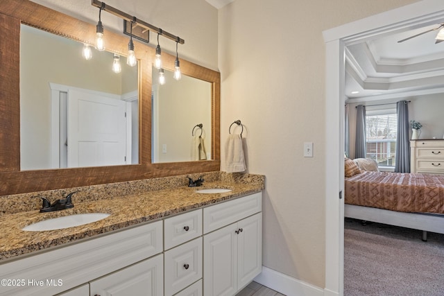 full bathroom with a tray ceiling, ensuite bathroom, ornamental molding, and a sink