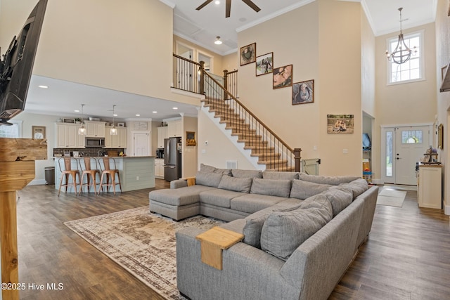 living room featuring crown molding, a towering ceiling, and dark wood-style flooring