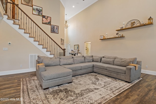 living area featuring visible vents, baseboards, a chandelier, wood finished floors, and stairway
