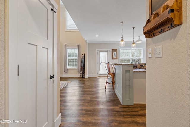 corridor with recessed lighting, a sink, crown molding, baseboards, and dark wood-style flooring