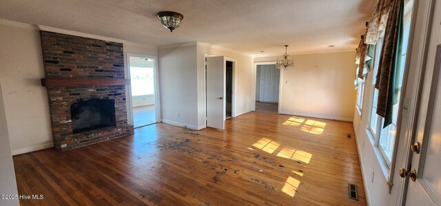 6693 NC-92, Bath, NC 27808 - unfurnished living room featuring a notable chandelier, a fireplace, crown molding, and wood finished floors