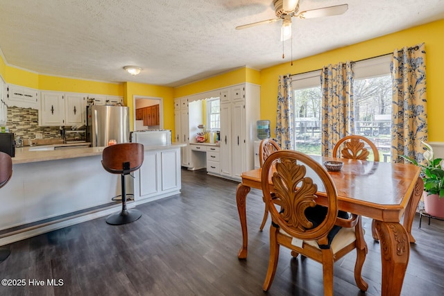 dining space with a ceiling fan, dark wood-type flooring, and a textured ceiling