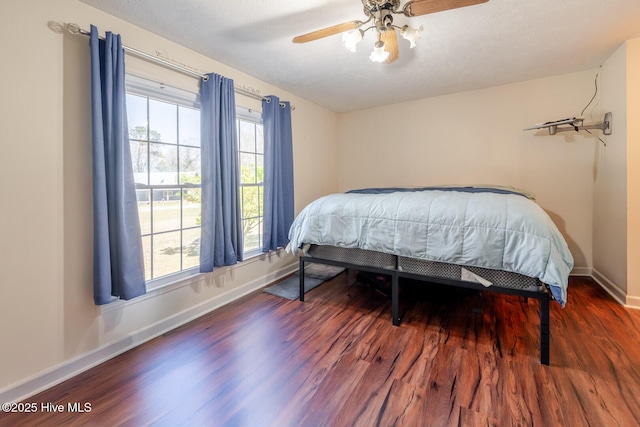 bedroom featuring ceiling fan, baseboards, and wood finished floors