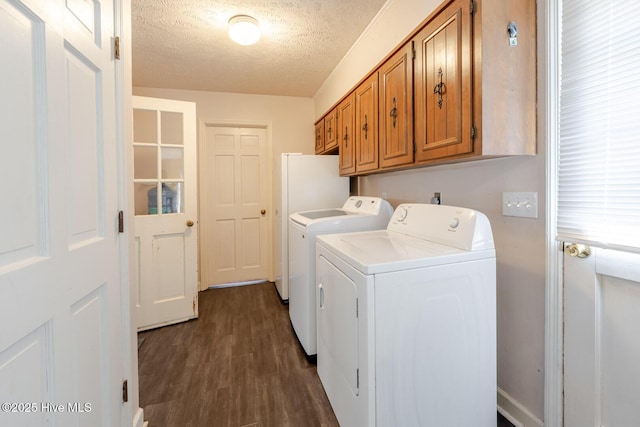 washroom featuring a textured ceiling, washing machine and clothes dryer, cabinet space, and dark wood-style flooring