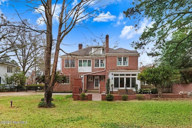 705 Park Ave, Goldsboro, NC 27530 - back of house with fence, a sunroom, a chimney, a lawn, and brick siding