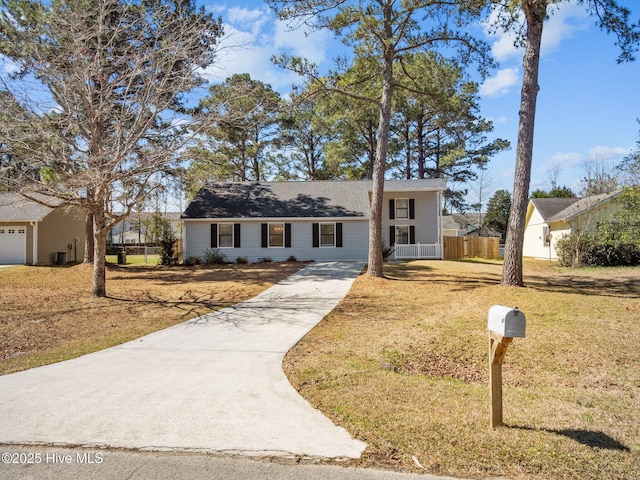 view of front of home with fence, concrete driveway, and a front yard