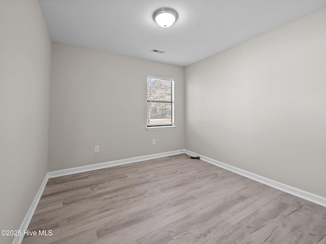 empty room with baseboards, visible vents, and wood finished floors