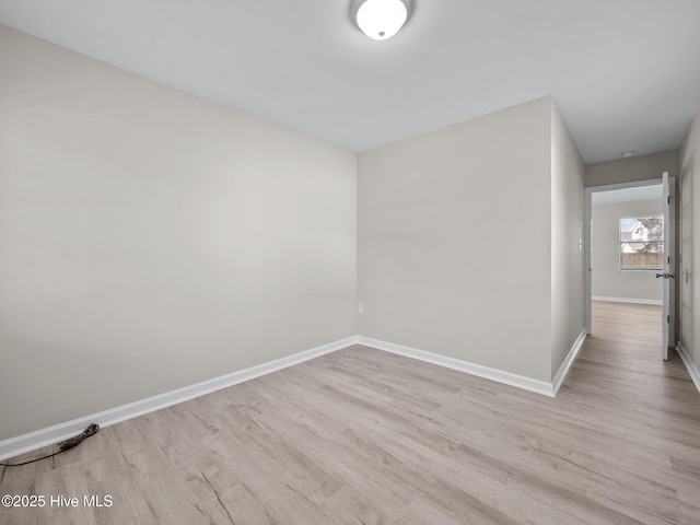 unfurnished room featuring baseboards and light wood-style floors