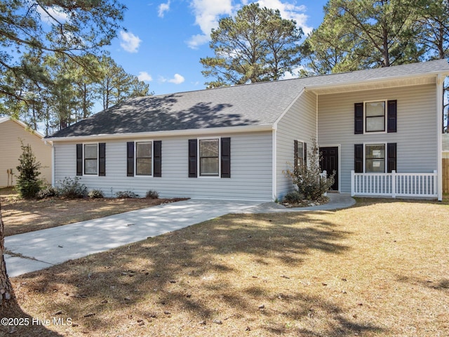 view of front of property with roof with shingles, covered porch, and a front yard