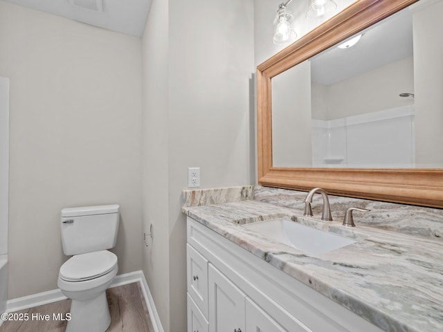 bathroom featuring vanity, toilet, baseboards, wood finished floors, and visible vents