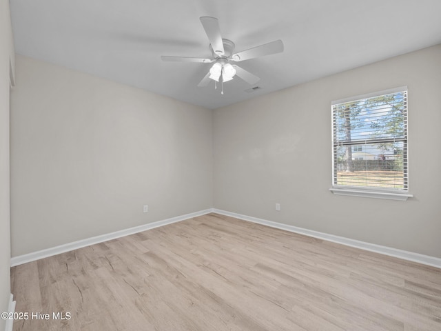 empty room with baseboards, a ceiling fan, light wood-type flooring, and visible vents