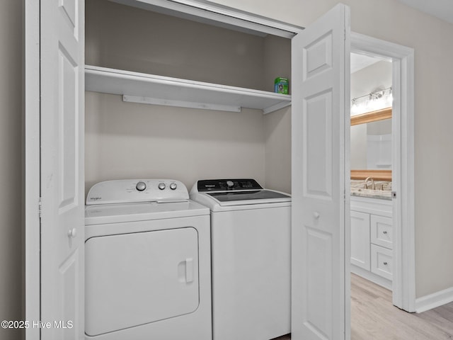 laundry room with a sink, laundry area, light wood-style flooring, and washing machine and clothes dryer