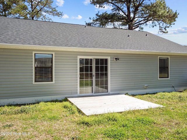 back of house with a lawn, a patio, and roof with shingles