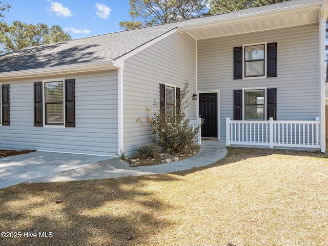 view of front of house featuring a porch, a shingled roof, and a front lawn