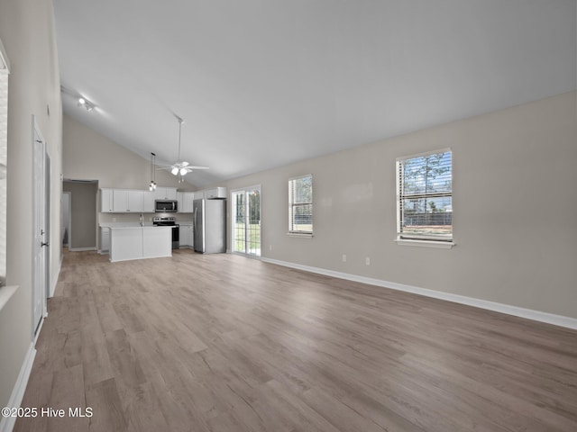 unfurnished living room with a healthy amount of sunlight, baseboards, a ceiling fan, and light wood-type flooring