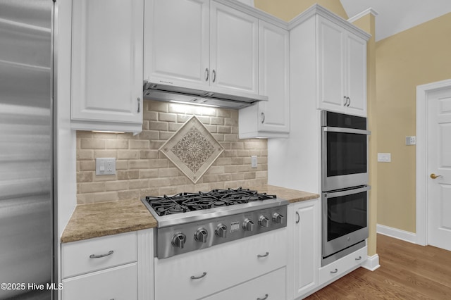 120 E High Bluff Dr, Hampstead, NC 28443 - kitchen featuring appliances with stainless steel finishes, exhaust hood, white cabinetry, and light wood-type flooring