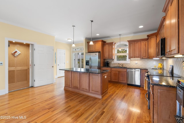 604 Fourth St S, Carolina Beach, NC 28428 - kitchen featuring stainless steel appliances, brown cabinets, light wood-style flooring, a kitchen island, and tasteful backsplash