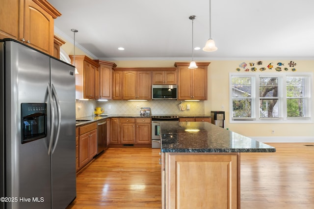604 Fourth St S, Carolina Beach, NC 28428 - kitchen featuring appliances with stainless steel finishes, ornamental molding, light wood-style floors, a center island, and tasteful backsplash