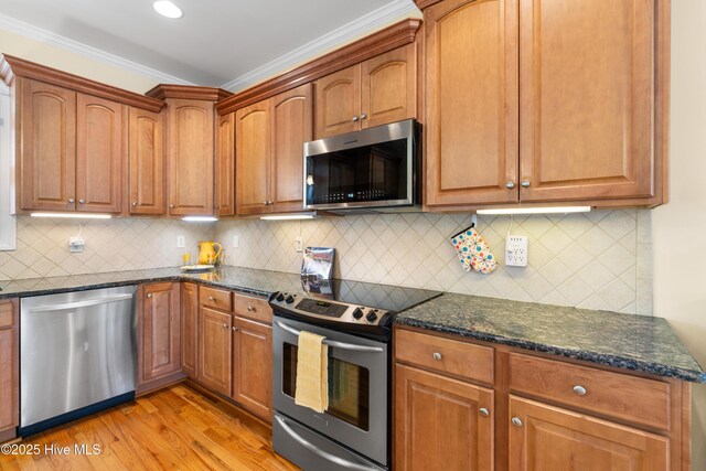 604 Fourth St S, Carolina Beach, NC 28428 - kitchen featuring stainless steel appliances, ornamental molding, dark stone counters, light wood finished floors, and backsplash