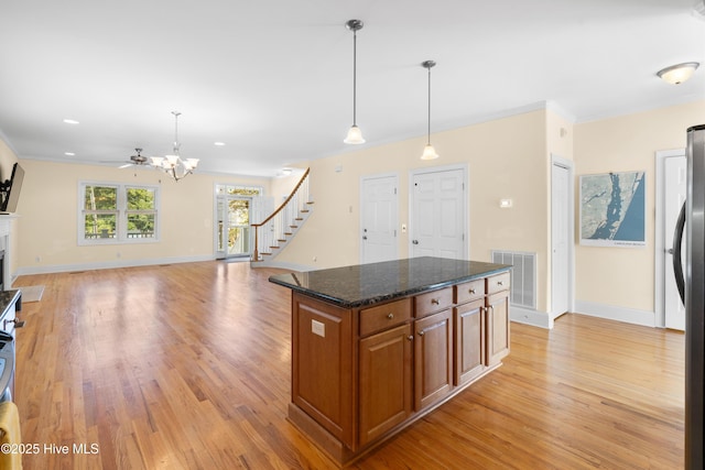604 Fourth St S, Carolina Beach, NC 28428 - kitchen with brown cabinets, light wood-style floors, ornamental molding, freestanding refrigerator, and decorative light fixtures