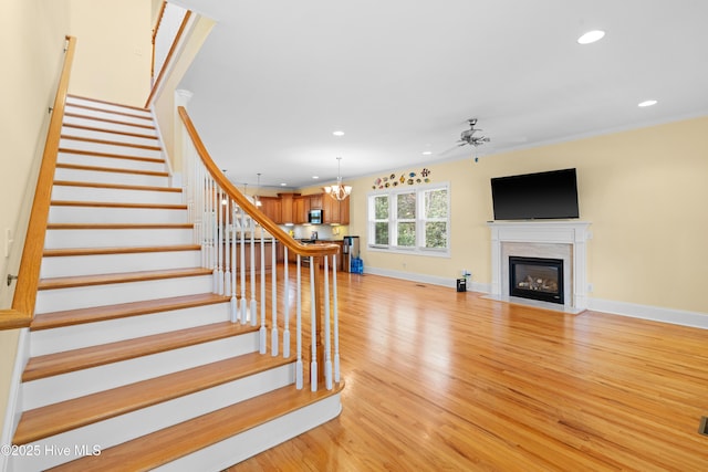604 Fourth St S, Carolina Beach, NC 28428 - stairway featuring wood finished floors, a ceiling fan, recessed lighting, a fireplace with flush hearth, and a chandelier