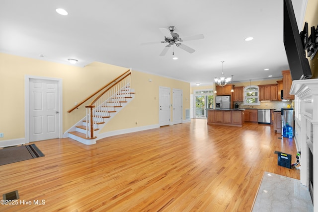 604 Fourth St S, Carolina Beach, NC 28428 - unfurnished living room featuring light wood finished floors, ceiling fan, stairs, a high end fireplace, and a chandelier