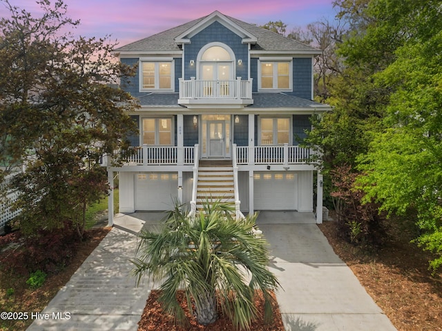604 Fourth St S, Carolina Beach, NC 28428 - coastal inspired home featuring a balcony, stairs, a garage, a shingled roof, and concrete driveway
