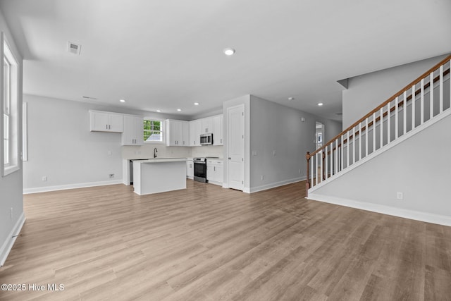 1007 Tawney Trce, New Bern, NC 28562 - unfurnished living room with baseboards, stairs, recessed lighting, and light wood finished floors